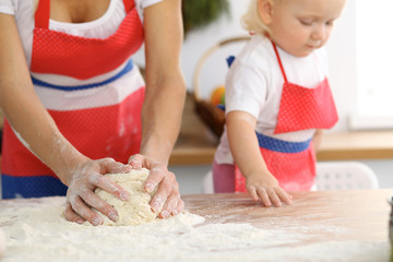 Obraz na płótnie Canvas Mother and her cute daughter hands prepares the dough on wooden table. Homemade pastry for bread or pizza. Bakery background
