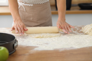 Female hands making dough for pizza or bread while using rolling pin. Baking concept
