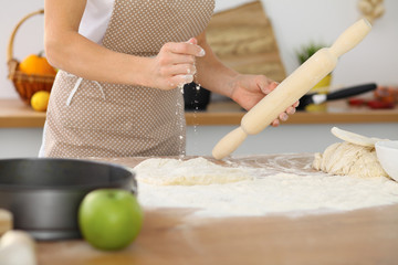 Female hands making dough for pizza or bread while using rolling pin. Baking concept
