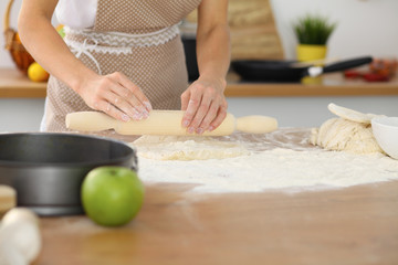 Female hands making dough for pizza or bread while using rolling pin. Baking concept
