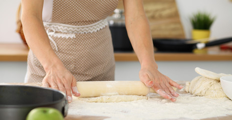 Female hands making dough for pizza or bread while using rolling pin. Baking concept