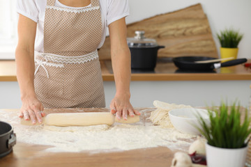 Female hands making dough for pizza or bread while using rolling pin. Baking concept