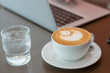 Hot art latte coffee cup on wooden table