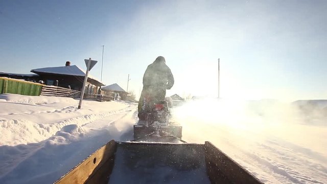 A man is riding a snowmobile in the village