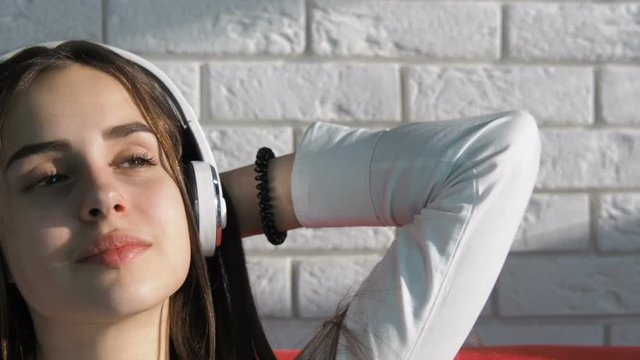Happy girl with headphones listening to music. Girl in headphones in the sun.