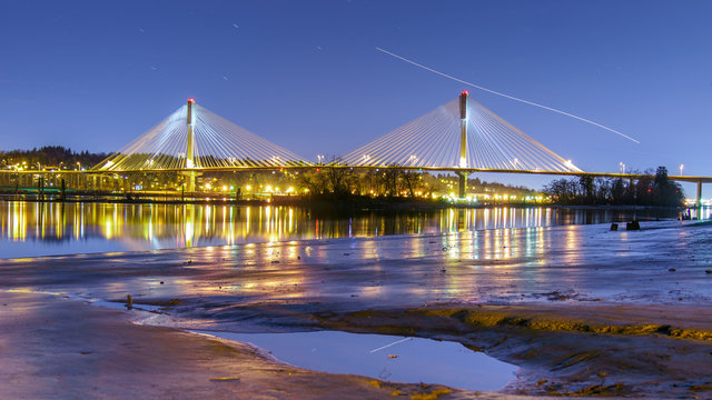 Port Mann Bridge, trail stars and airplanes into the sky. Long exposure in a bright night. Vancouver, British Columbia, Canada.