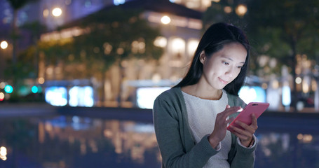 Woman looking at smart phone in city at night