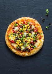 Taco vegetarian pizza. Mexican pizza with beans, corn, jalapeno pepper, mozzarella cheese on a dark background, top view. Snack, snack, tapas