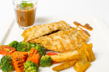 Grilled chicken breast with vegetable, baked potatoes, and a glass of black pepper gravy on white background