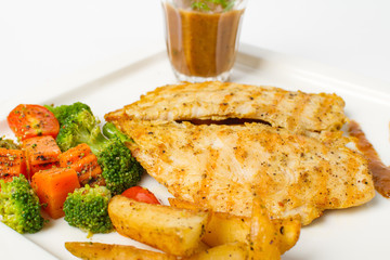 Grilled chicken breast with vegetable, baked potatoes, and a glass of black pepper gravy on white background