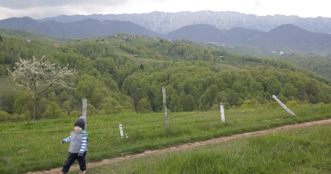 Happy boy running on rural village, beautiful spring landscape, green  4K
