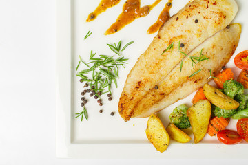 Grilled fish fillets steak served with mix vegetable, potatoes and a glass of black pepper gravy sauce on white background
