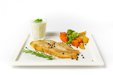 Grilled fish fillets steak served with mix vegetable, potatoes and a glass of white cream sauce on white background