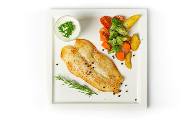 Grilled fish fillets steak served with mix vegetable, potatoes and a glass of white cream sauce on white background