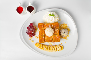 Desserts, Toast topped with vanilla ice cream, served with whipping cream, grape, banana, bean, honey and strawberry sauce on white background