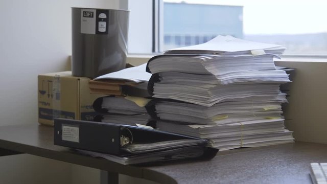 Stack of office files, records and binders on a desk