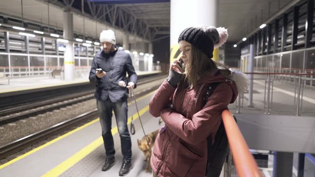 Teenage girl talking on cellphone while waiting for train at night
