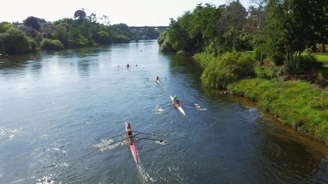 Drone shot of woman rowing down a clear blue river in New Zealand.