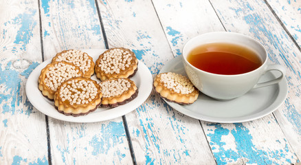 Cup of tea and saucer with cookies on the table.