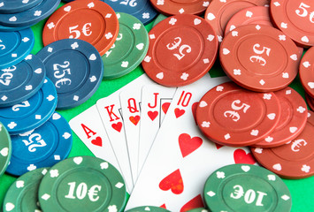 Poker chips with playing cards on the green background.