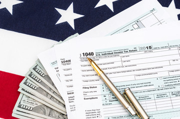Tax forms with money and pen on american flag. Tax concept.