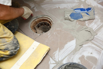 Grouting ceramic tiles on the floor by a man.