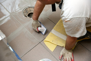 Grouting ceramic tiles on the floor by a man.