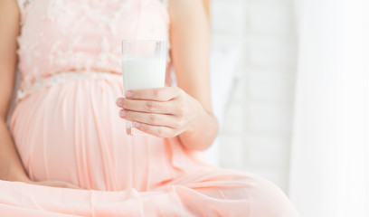 Selective focus  Pregnancy woman  in pink dress holding a glass of milk  on the bed in bedroom.