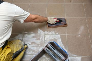 Grouting ceramic tiles on the floor by a man.