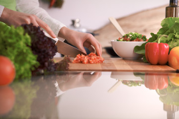 Close Up of human hands cooking vegetable salad in kitchen on the glass table with reflection. Healthy meal, and vegetarian food concept
