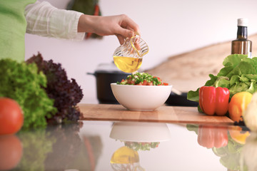 Close Up of human hands cooking vegetable salad in kitchen on the glass table with reflection. Healthy meal, and vegetarian food concept
