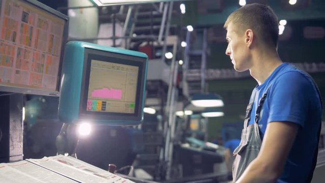 Worker using touchscreen operating industrial machine.