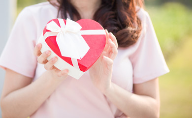 Selective focus Woman hold red gift heart box in the park .  Concept of the Valentine's Day.