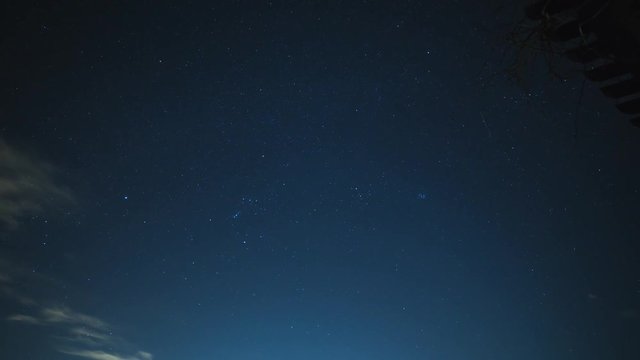 Time lapse of dark night sky with clouds, stars, and streaks of light.