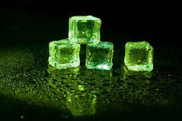 Green ice cubes on black background.