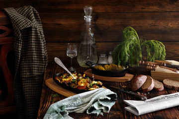 жареный картофель в чугунной сковороде и бутылка водки на столе