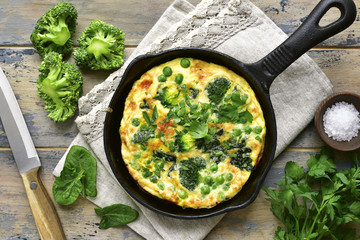 Omelette printanière aux légumes verts (brocoli, pois de senteur et épinards) dans une poêle.Vue de dessus.