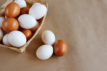 white and brown eggs in a straw basket on a craft background