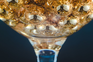 Gold beads in the wine glass with water, bubbles, macro, photo, background for design or Wallpaper.