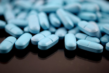 Bright blue oval tablets closeup on black background