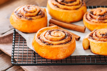 Obraz na płótnie Canvas Classic cinnamon rolls - cinnabons with crean cheese frostind with smarties. Wooden background.