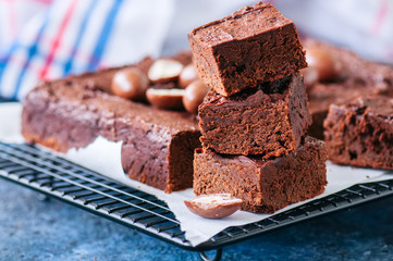 Dark chocolate brownie squares on a wire rack decorated with creamy chocolate eggs. Blue stone background.