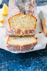 Homemade lemon poppy seed pound cake on a wire rack. Blue stone background. Close up.
