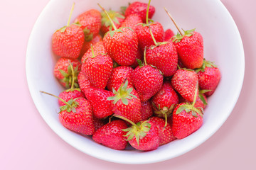 fresh strawberry in the white bowl on pink background