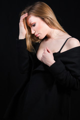 Fototapeta premium Sexy lady with glamour makeup and long blonde hair in underwear and long coat posing in studio. Elegant woman wearing black sensual lingerie. Erotic noir concept.