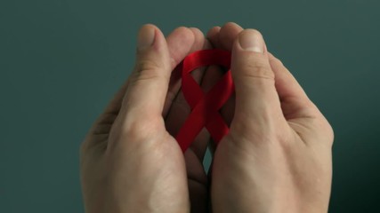 HIV/AIDS red awareness ribbon in the hands.
