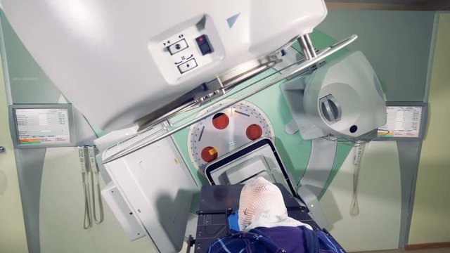Massive linear accelerator is revolving around a male patient
