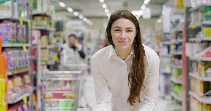 Beautiful girl smiling at the camera with a supermarket in the background
