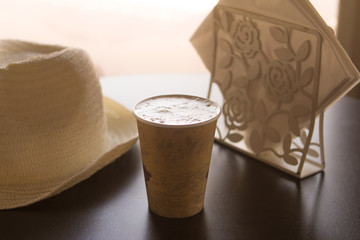 a cup of coffee on a table in a cafe with a white hat and white napkins