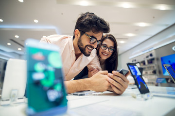 Close up focus view of a cheerful charming happy young student love couple choosing a new mobile in...